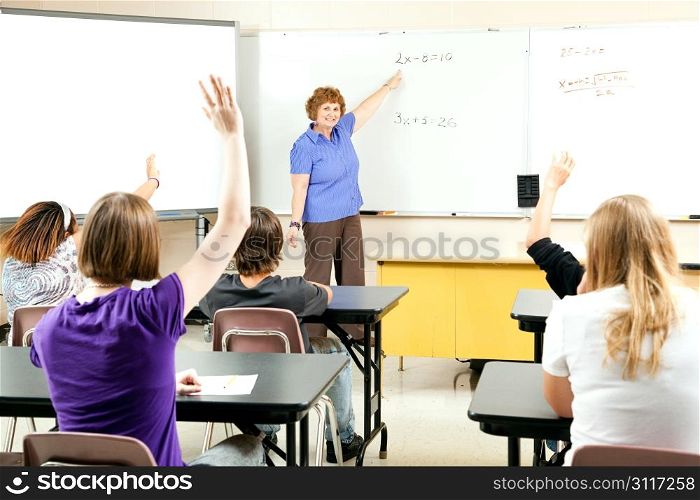 Students raise their hands to solve a problem in algebra class.