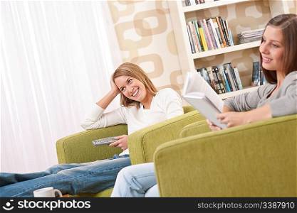 Students - Two female student relaxing home watching TV and reading book