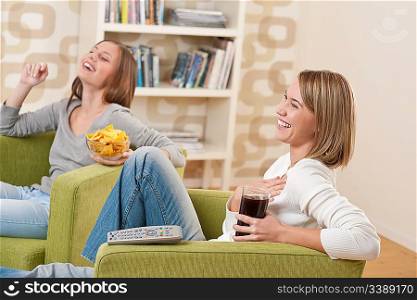 Students - Two smiling female teenager watching television together, eating crisps