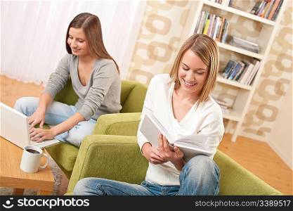 Students - Two teenage girls with laptop and book in modern lounge