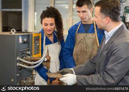 Students watching instructor use industrial machine