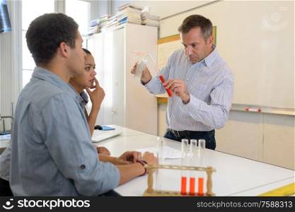 students watching teacher drip reagent into test tube