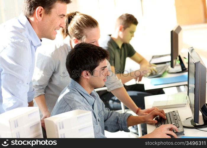 Students with teacher in front of desktop computer