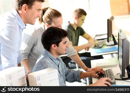 Students with teacher in front of desktop computer