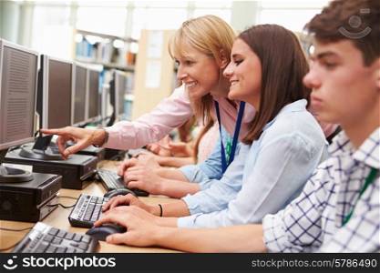 Students Working At Computers In Library With Teacher