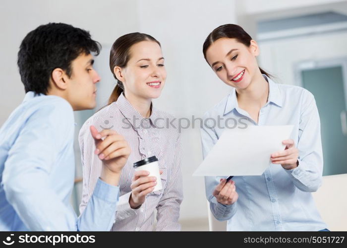 Students working in cooperation. Three students working in cooperation using laptop while having coffee