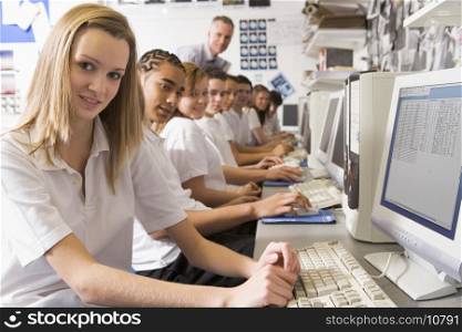 Students working on computer workstations with teacher