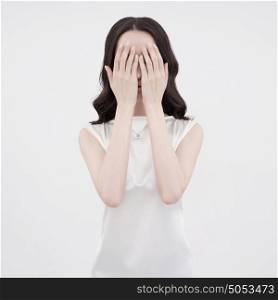 Studio art fashion photo of woman closing her face with her hands on white background. Health and beauty