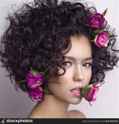 Studio fashion photo of beautiful young woman with flowers in her mouth and hair. Valentines day. Spring blossom