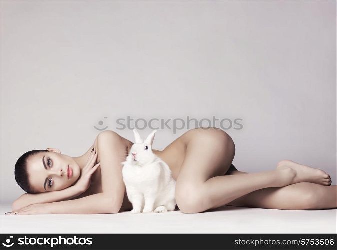 Studio fashion photo of naked elegant lady with white rabbit