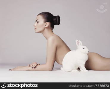 Studio fashion photo of naked elegant lady with white rabbit