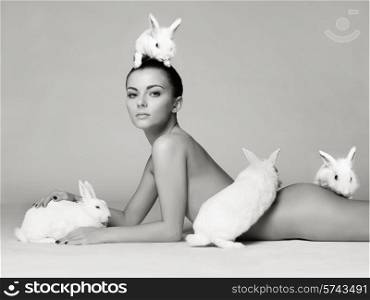 Studio fashion photo of naked elegant lady with white rabbits