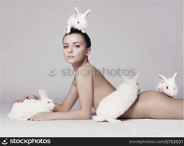 Studio fashion photo of naked elegant lady with white rabbits