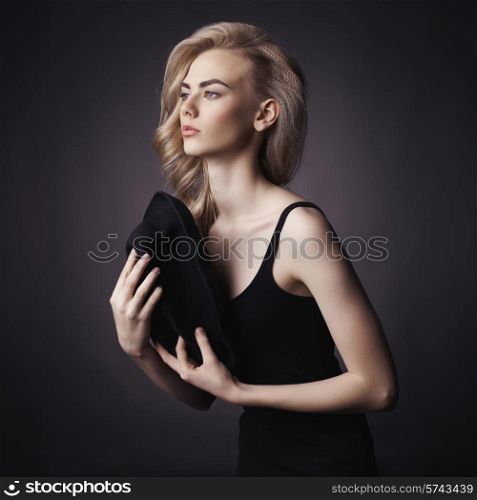 Studio fashion portrait of beautiful lady with hat in her hand