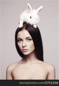 Studio fashion portrait of beautiful lady with white rabbit