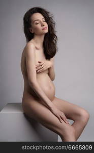 Studio fashion portrait of beautiful pregnant woman. Pretty naked lady.Happy pregnancy. Beauty and health.      