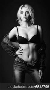 Studio fashion shot: a sensual beautiful young woman in denim and underwear. Black and white