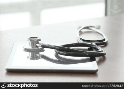 studio macro of a stethoscope and digital tablet on wood table background copy space