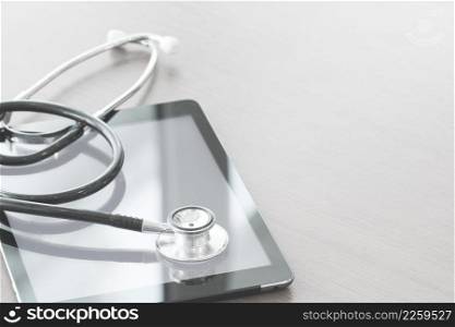 studio macro of a stethoscope and digital tablet on wood table background copy space