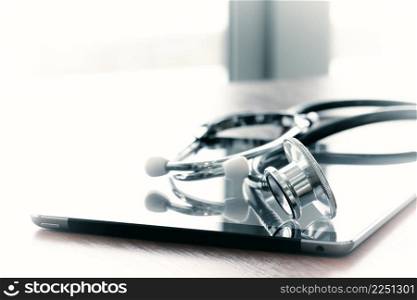Studio macro of a stethoscope and digital tablet with shallow DOF evenly matched abstract on wood table background copy space