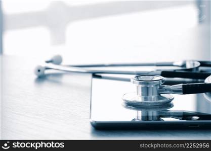 Studio macro of a stethoscope and digital tablet with shallow DOF evenly matched abstract on wood table background copy space
