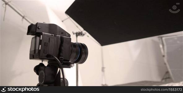 Studio medium format digital camera setup on tripod and professional equipment in studio with black and white color softbox and lighting set for still photo shooting or high resolution video or movie works