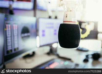 Studio microphone in a broadcasting radio studio, mixer and computer in the blurry background