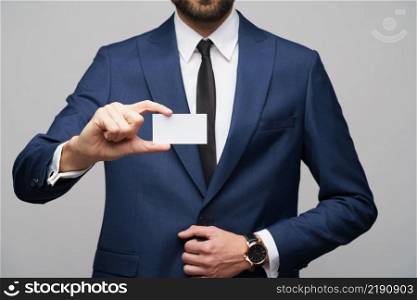 studio photo of young caucasian handsome businessman wearing suit holding business card. studio photo of young handsome businessman wearing suit holding business card
