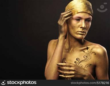 Studio portrait. Artwork on woman body painted in gold