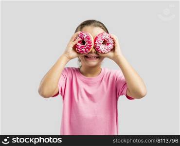 Studio portrait of a beautiful little girl looking through a donut