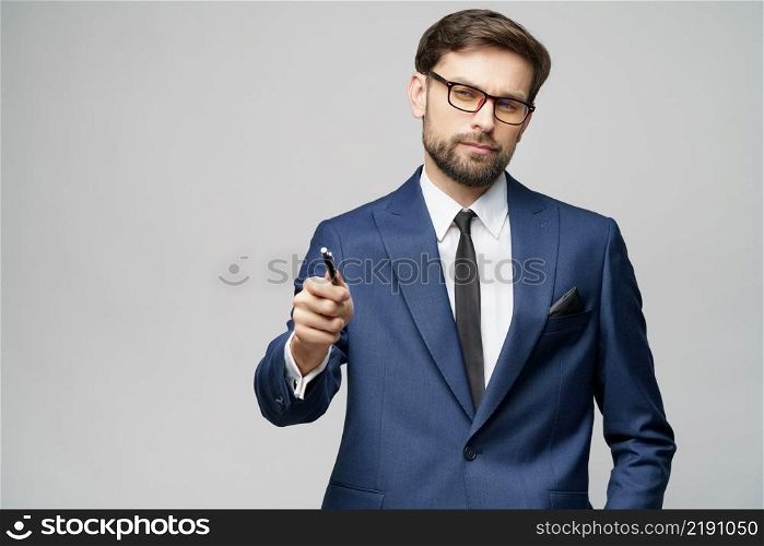 Studio Portrait of a businessman showing pen or pencil at camera over gray background. Portrait of a businessman showing pen or pencil at camera over gray background