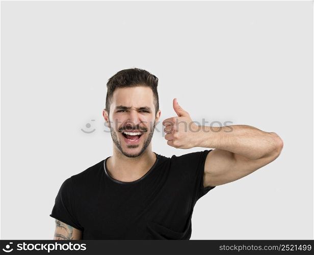 Studio portrait of a funny young man smiling and with thumsb up