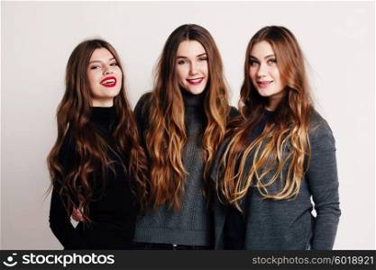 Studio portrait of a group of three young beautiful model smiling and having fun. Consumer concept, winter fashion, attractive young women