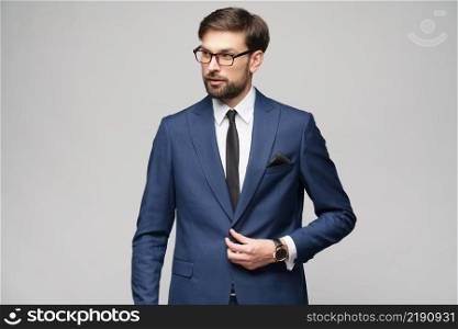 Studio Portrait of a handsome young stylish businessman wearing glasses over grey background. Portrait of a handsome young stylish businessman wearing glasses over grey background