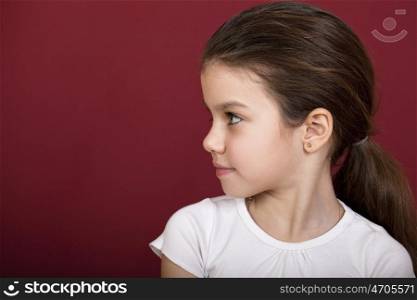 studio portrait of a pretty little girl on a burgundy background