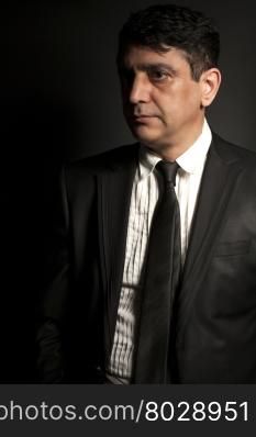 Studio portrait of a serious businessman wearing a black suit on black background