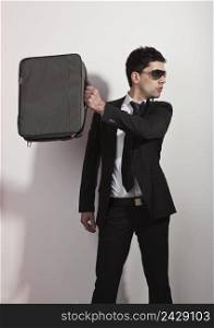 Studio portrait of a young businessman holding a suitcase