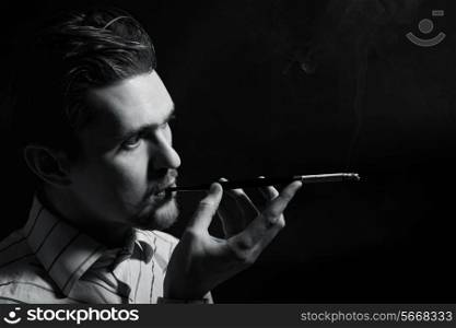Studio portrait of a young man smoking a cigarette on a black background