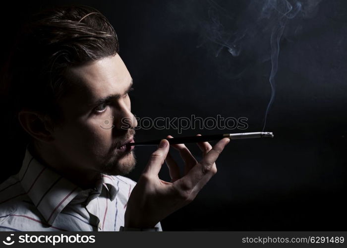 Studio portrait of a young man smoking a cigarette on a black background