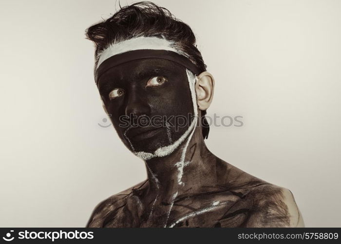 Studio portrait of a young man with a black theatrical makeup on white background