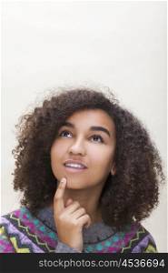 Studio portrait of beautiful happy mixed race African American girl teenager female young woman looking up thinking, dreaming or wishing