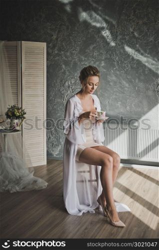 Studio portrait of bridesmaid duties before the wedding ceremony.. Portrait of a young girl in a chic translucent negligee in the Studio 331.