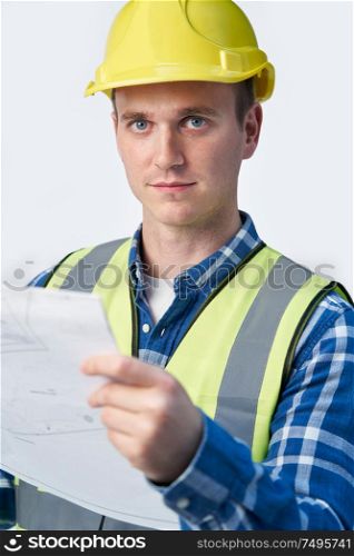 Studio Portrait Of Builder Architect Looking At Plans Against White Background