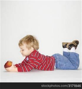 Studio portrait of Caucasian boy holding apple against white background.