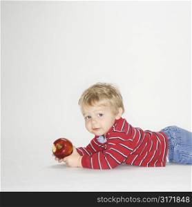 Studio portrait of Caucasian boy holding apple against white background.