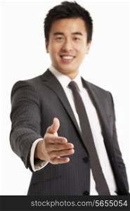 Studio Portrait Of Chinese Businessman Reaching Out To Shake Hands