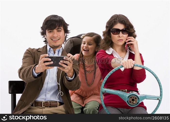 Studio portrait of distracted family in imaginary car