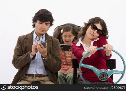 Studio portrait of distracted family in imaginary car