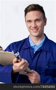 Studio Portrait Of Male Engineer With Clipboard And Spanner Against White Background