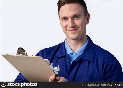 Studio Portrait Of Male Engineer With Clipboard And Spanner Against White Background